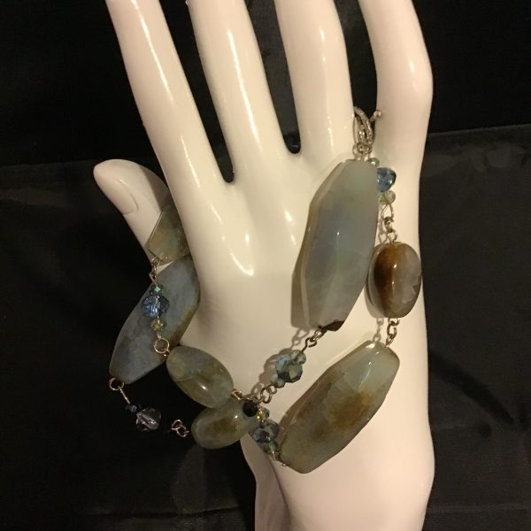 A bold, ocean-inspired statement bracelet featuring faceted blue stones, shimmering beads, and earthy undertones for a naturally elegant look.