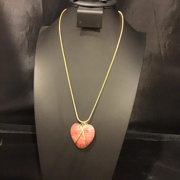 A captivating vermilion heart pendant suspended on a fine golden chain, embodying passion with a touch of vintage charm.
