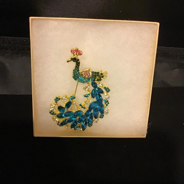 Make your style as regal as a peacock with this captivating brooch, featuring a gold-tone body, pink crystal crest, and a splendid blue crystal tail.