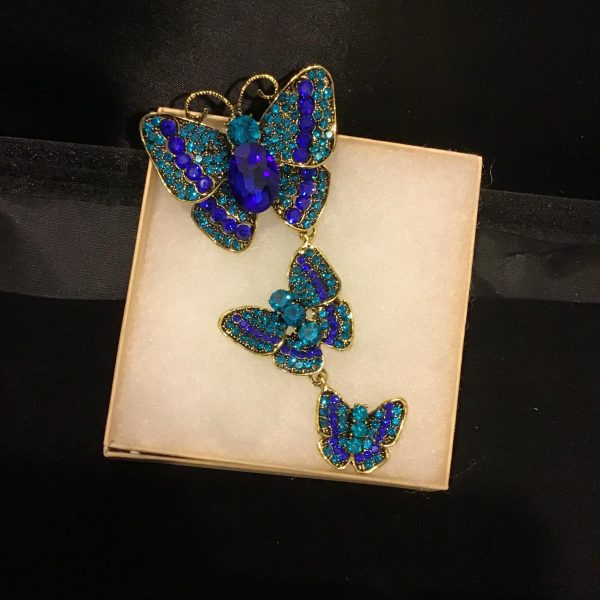 Elevate your accessory collection with the "Sapphire Flutter," a vintage brooch adorned with sparkling blue rhinestones and a majestic central gem. A perfect fusion of color and elegance to complement any attire.