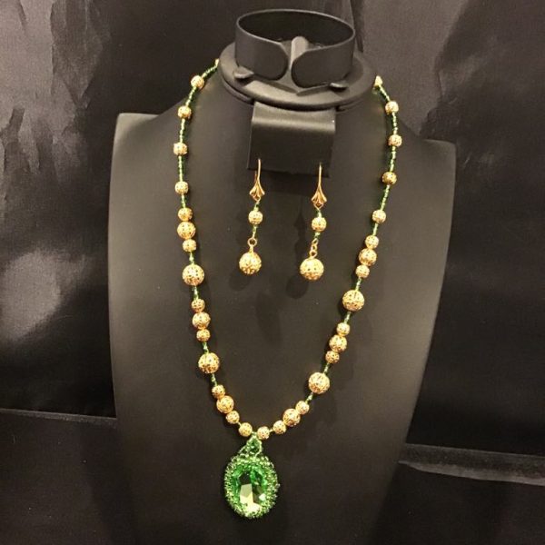 A mesmerizing gold-toned beaded necklace set with a radiant emerald-green pendant and matching earrings, perfect for elegant occasions.