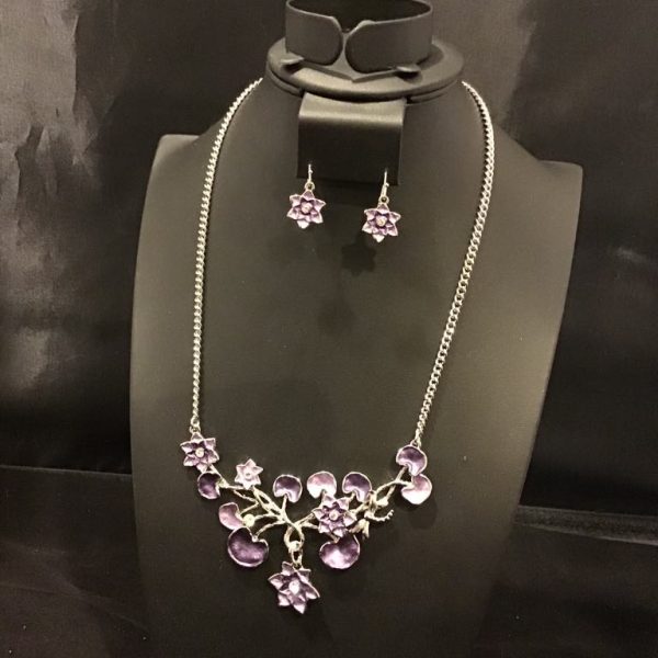 A delicate floral statement, this enchanting necklace and earring set features radiant purple blossoms intertwined with elegant silver-toned branches, perfect for adding a whimsical touch to any outfit.