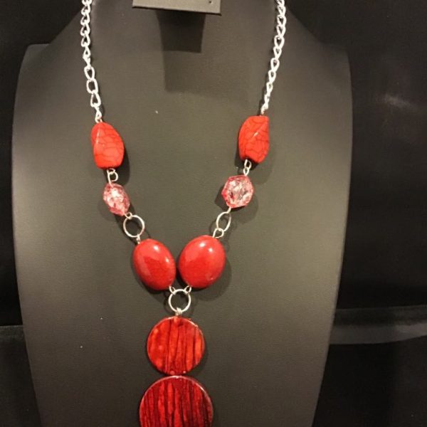 A bold statement necklace featuring striking red beads, textured pendants, and a silver-tone chain for a dramatic and elegant look.