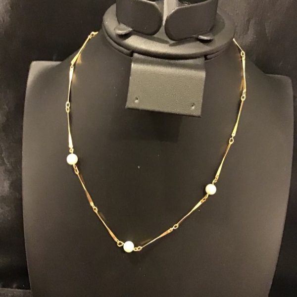 A delicate gold-tone station necklace featuring elegant pearls and sleek bar-link details—perfect for timeless sophistication.
