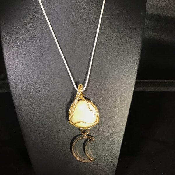 Elevate your style with the Moonlit Whisper Amulet Necklace, featuring a luminous stone wrapped in golden wire and a celestial crescent moon charm.