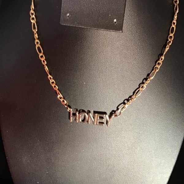 Add a playful twist to your outfit with our Sweet Honey Gold-Tone Necklace, featuring a bold “HONEY” pendant and vintage-inspired chain links.